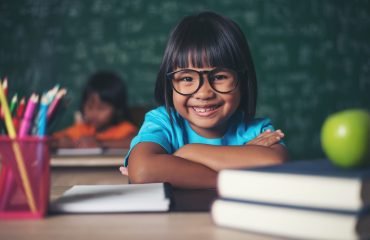 Portrait of smiling schoolgirl sitting at the table with books