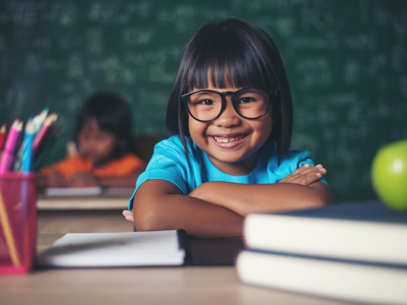 Portrait of smiling schoolgirl sitting at the table with books